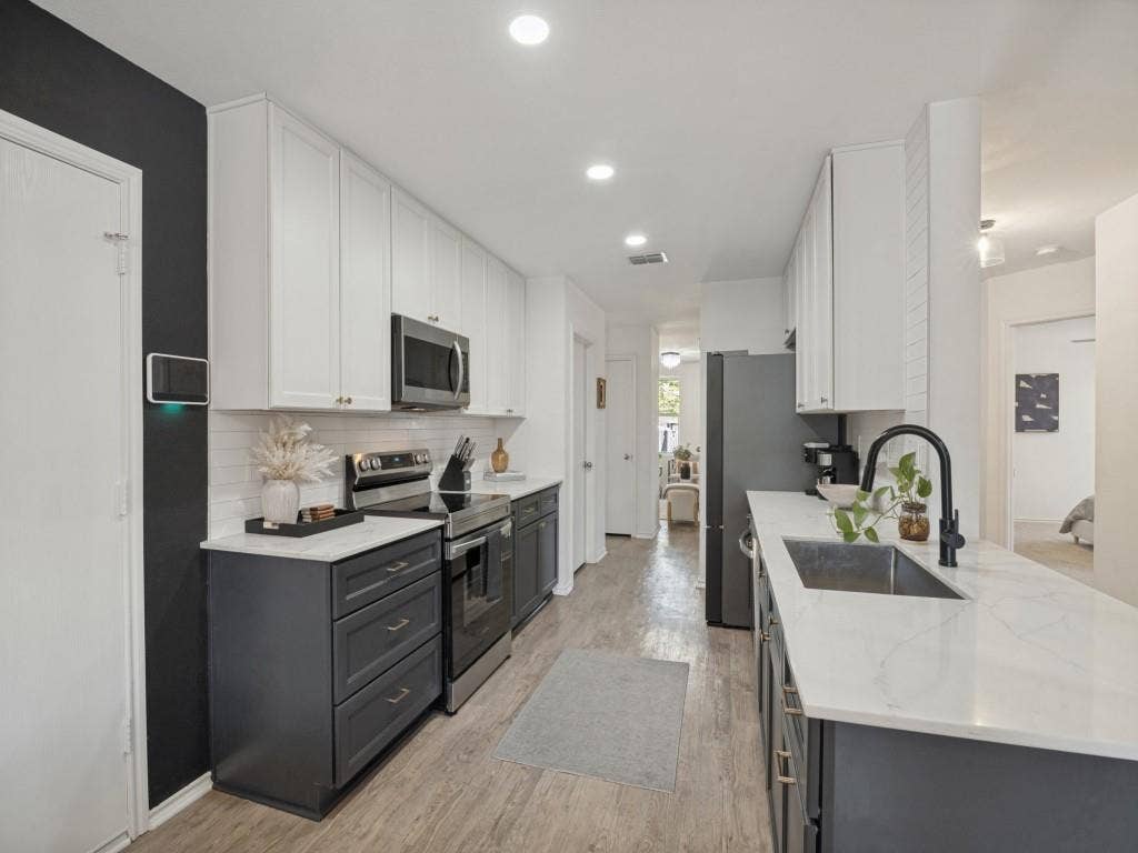 1728 Harvest Crossing Drive, Wylie, TX 75098 Kitchen featuring two-tone cabinetry, stone-finish countertops, subway tile backsplash, stainless steel appliances, and a matte black gooseneck faucet