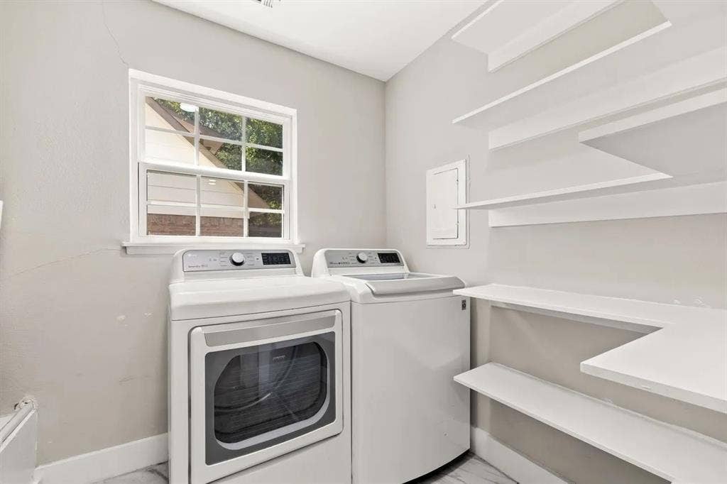 Laundry room featuring built-in wall shelving, a single-hung window with a grid pattern, and light-toned flooring