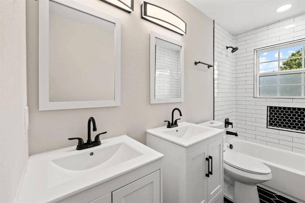 Dual white vanities featuring rectangular undermount sinks, matte black widespread faucets, subway tile shower surround, and hexagonal patterned tile flooring