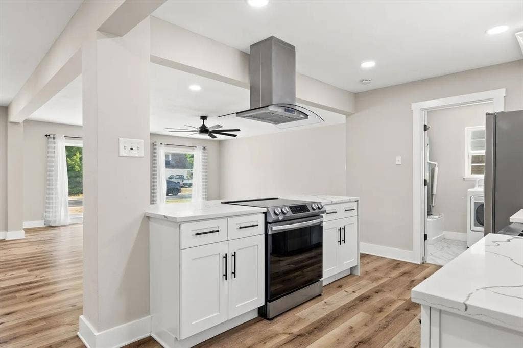 Kitchen featuring white cabinetry, quartz countertops, wood-finish flooring, a stainless steel range, and a stainless steel chimney-style range hood