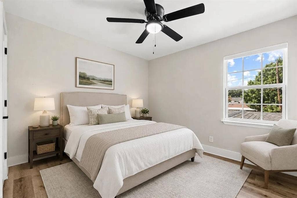 Bedroom featuring neutral wall tones, wood-finish flooring, a multi-pane window, and a central ceiling fan with an integrated light fixture
