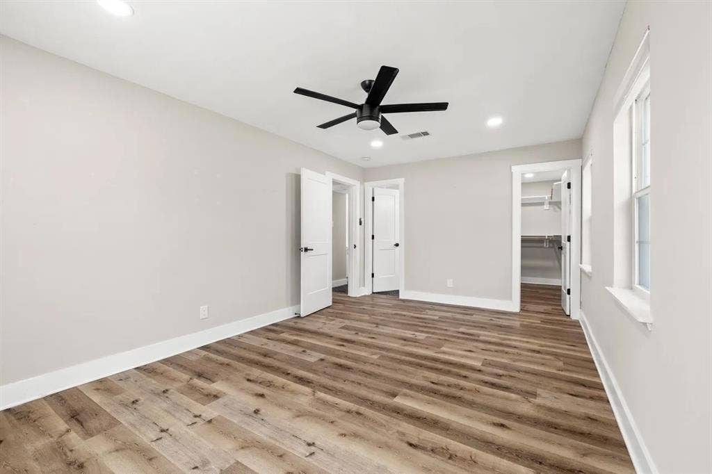 Interior room featuring wood-finish flooring, recessed lighting, a multi-blade ceiling fan, and a walk-in closet with built-in shelving