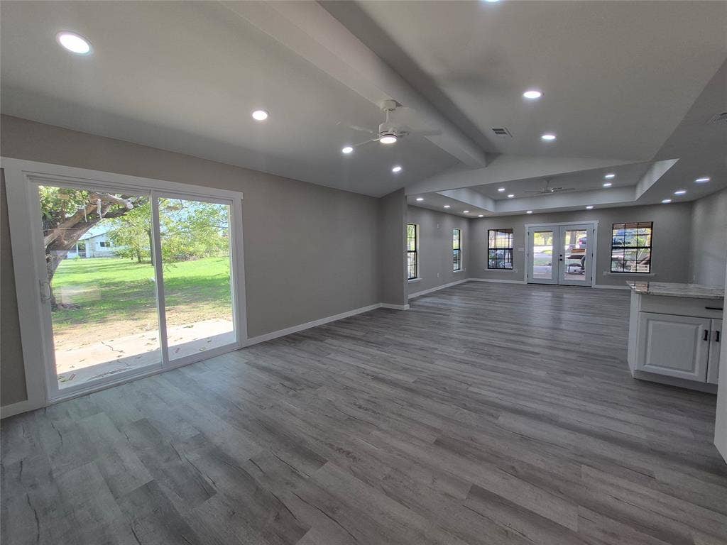 2029 Roberts Drive, Granbury, TX 76048 Open-concept interior featuring wood-finish flooring, recessed lighting, vaulted ceilings, a sliding glass door, and white cabinetry with stone-finish countertops