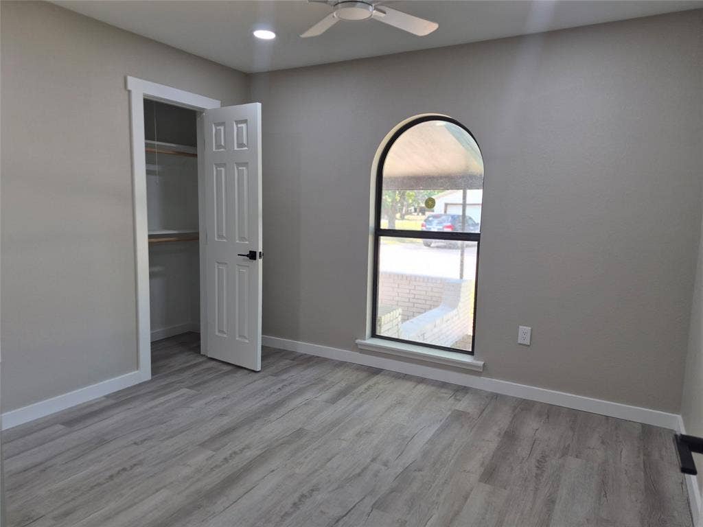 2029 Roberts Drive, Granbury, TX 76048 Interior space featuring wood-finish flooring, an arched window, a ceiling fan, and a walk-in closet with built-in shelving