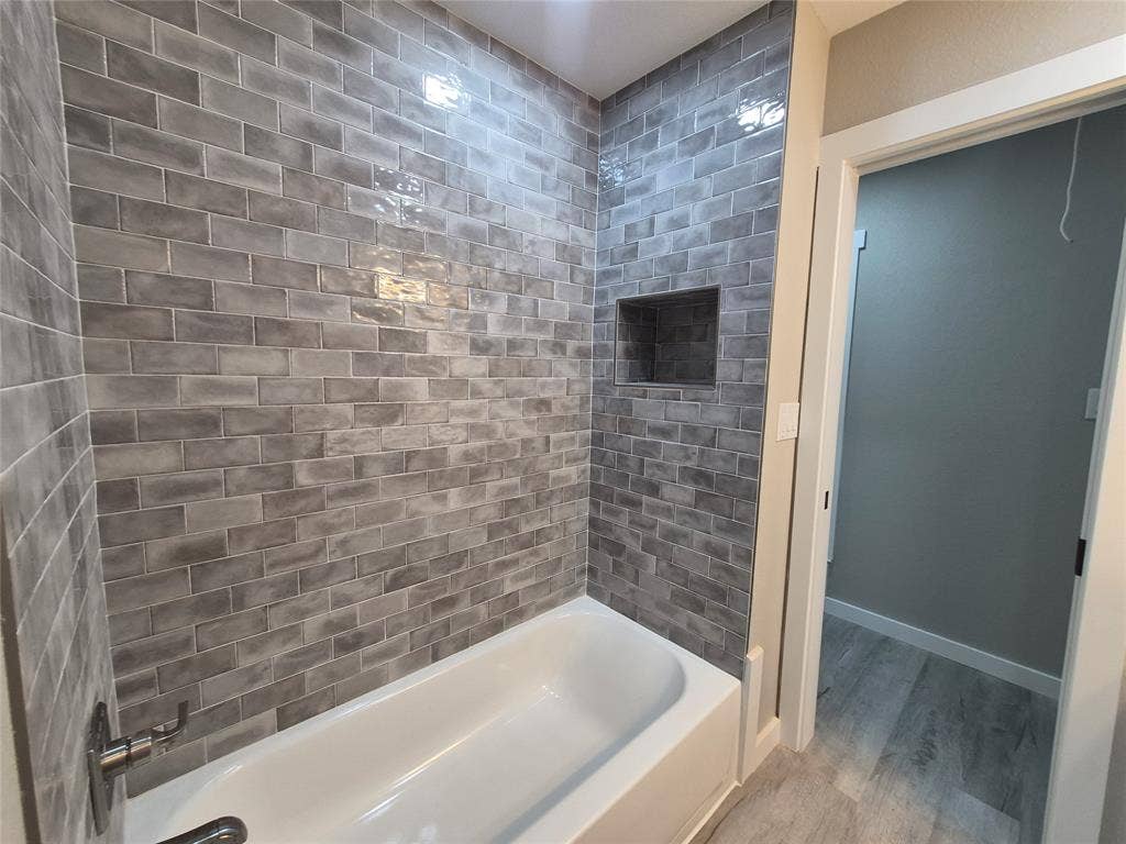 2029 Roberts Drive, Granbury, TX 76048 Tiled shower surround featuring glazed gray brick-style subway tiles, built-in recessed wall niche, and polished chrome hardware