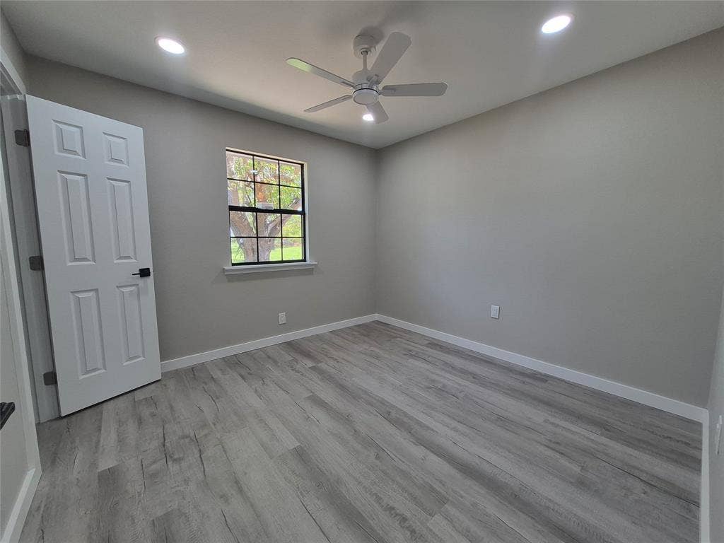2029 Roberts Drive, Granbury, TX 76048 Neutral-toned interior featuring wood-finish flooring, recessed lighting, a ceiling fan with integrated light kit, and a multi-pane window