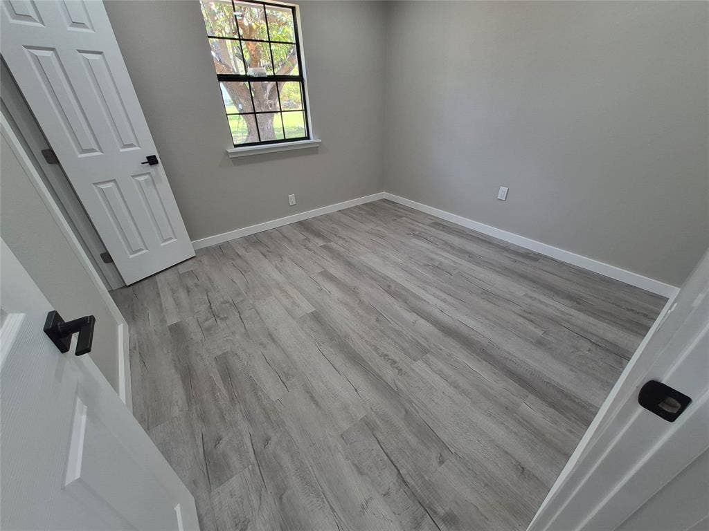 2029 Roberts Drive, Granbury, TX 76048 Room featuring wood-finish flooring, a single-hung window with a grid pattern, and interior doors with matte black hardware