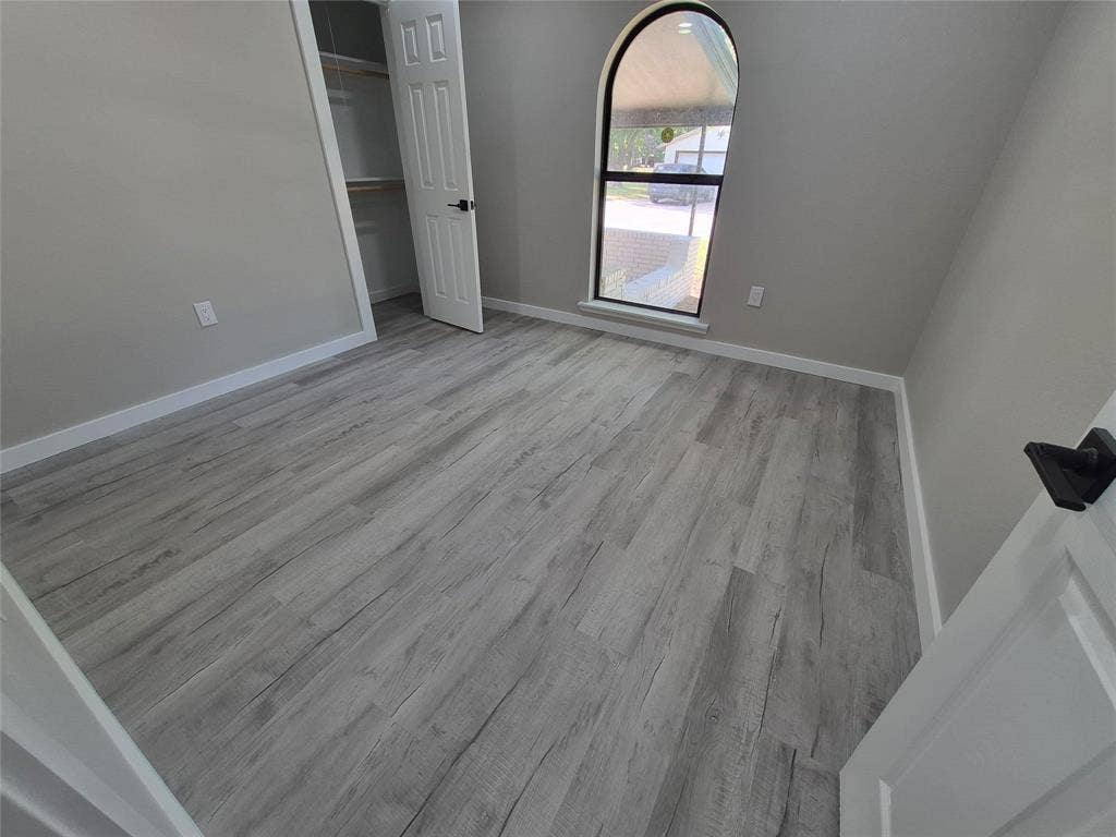 2029 Roberts Drive, Granbury, TX 76048 Room featuring wood-finish flooring, an arched window, and a built-in closet with six-panel door