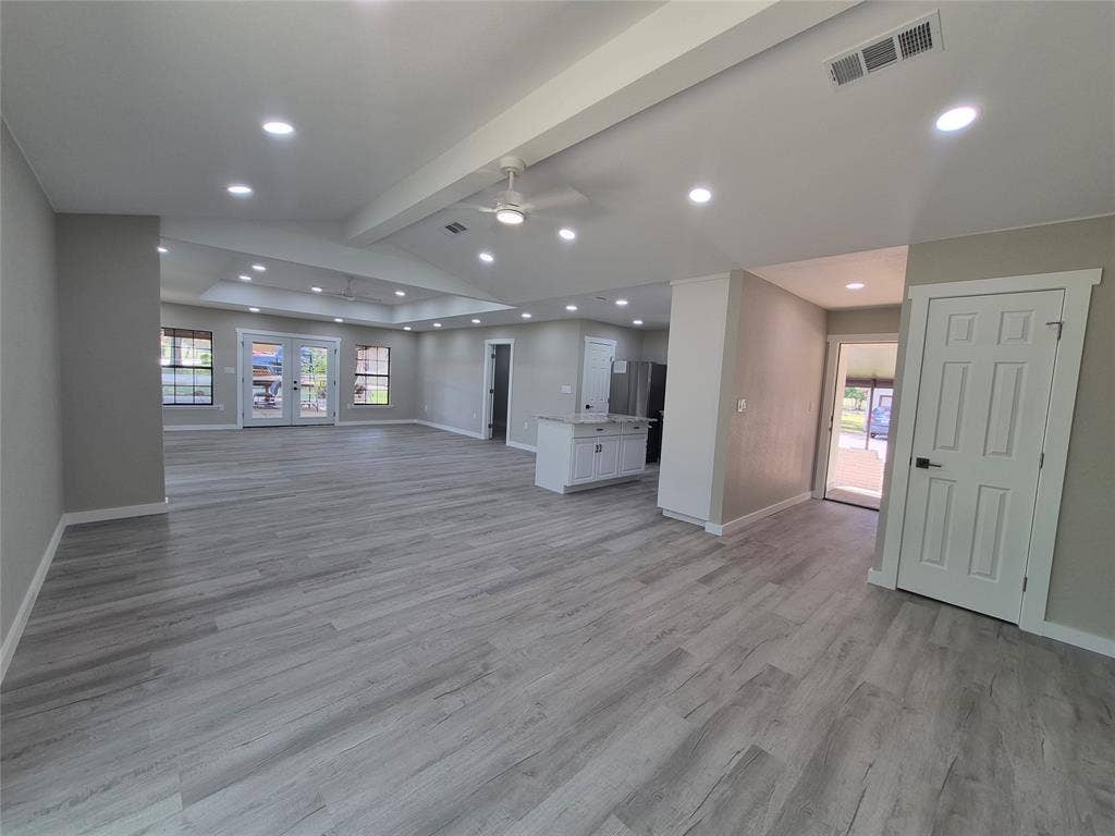 2029 Roberts Drive, Granbury, TX 76048 Open-concept interior featuring wood-finish flooring, recessed lighting, vaulted tray ceiling, and a central kitchen island with light-toned stone-finish countertop