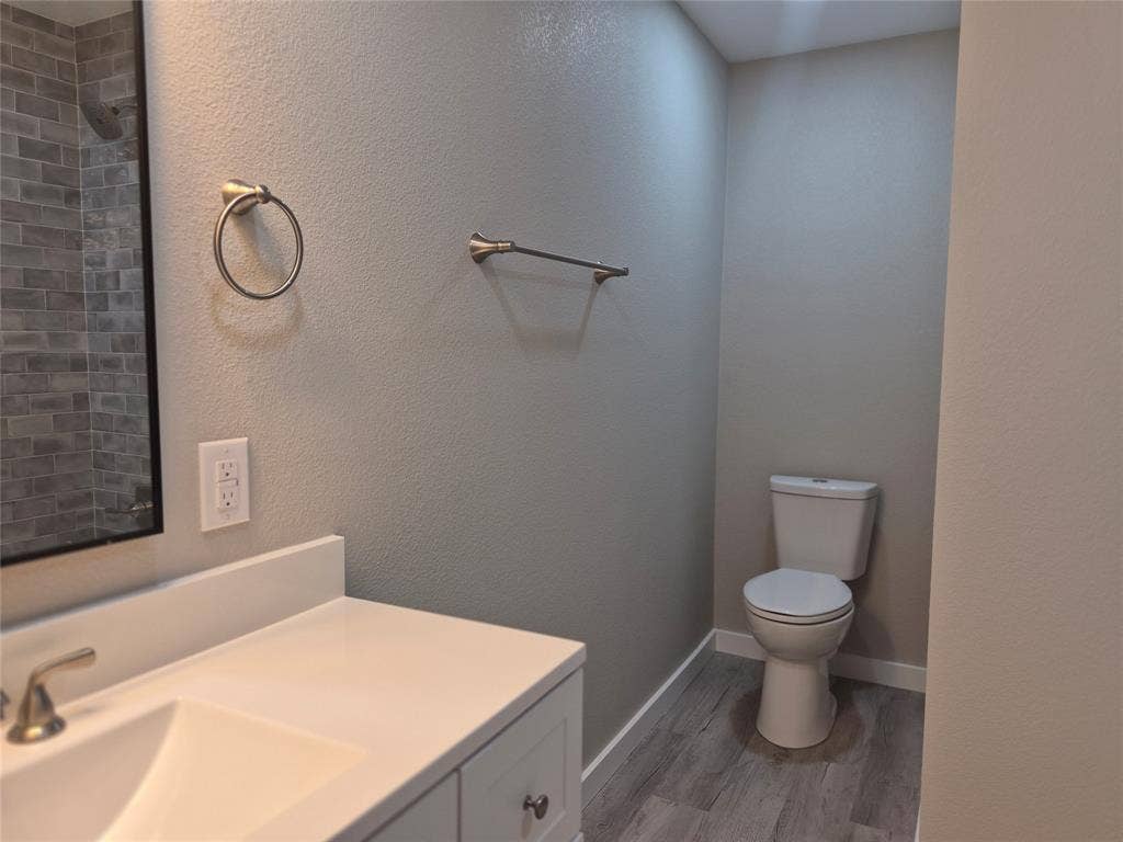 2029 Roberts Drive, Granbury, TX 76048 Bathroom featuring a white vanity with a solid-surface countertop, rectangular basin, wood-finish flooring, and subway tile shower surround