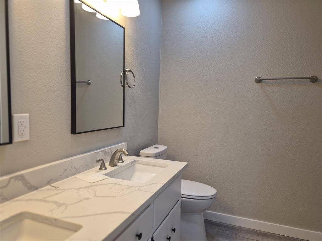 2029 Roberts Drive, Granbury, TX 76048 Double vanity featuring stone-surfaced countertops, undermount rectangular sinks, modern framed mirrors, and brushed-finish fixtures