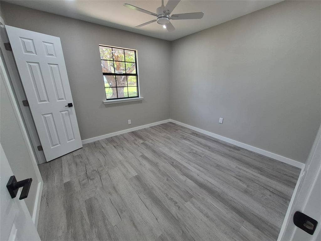 2029 Roberts Drive, Granbury, TX 76048 Room featuring wood-finish flooring, a multi-pane window, a ceiling fan, and six-panel interior doors with matte black hardware