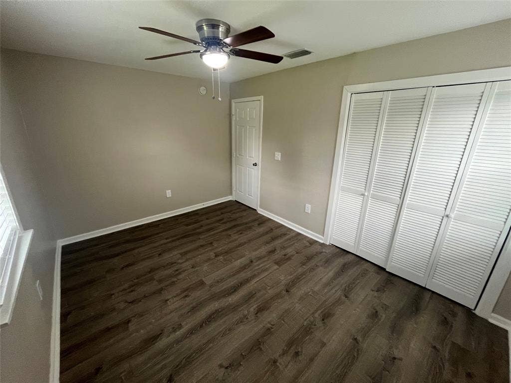 6415 Godfrey Avenue, Dallas, TX 75217 Room featuring wood-finish flooring, a ceiling fan with integrated lighting, and a large closet with louvered double doors