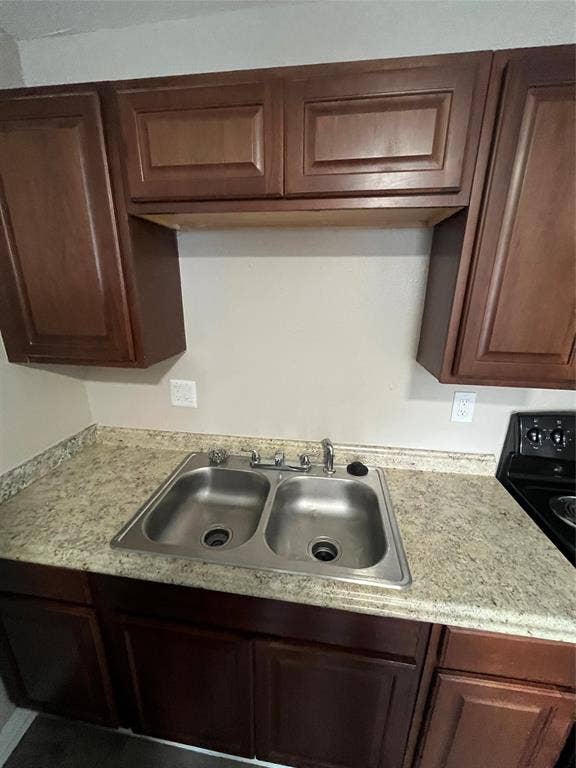 6415 Godfrey Avenue, Dallas, TX 75217 Raised-panel wood cabinetry, laminate countertops, dual-basin stainless steel sink, and chrome finish faucet
