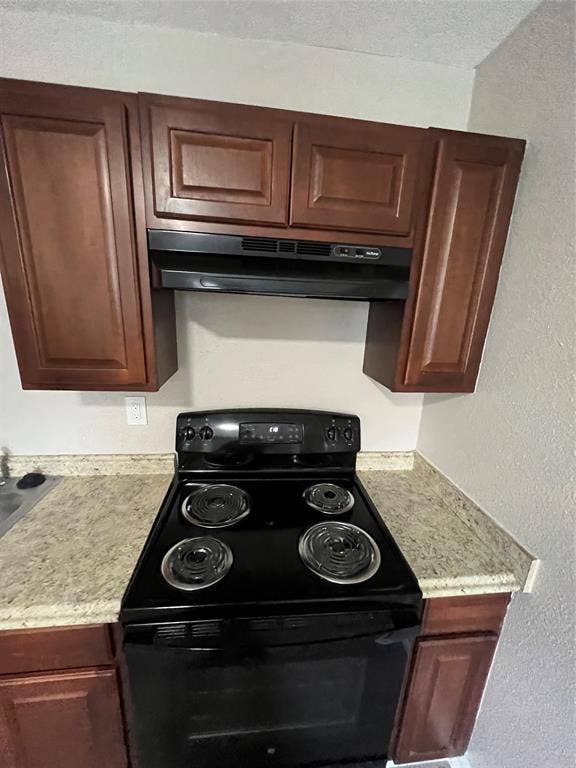 6415 Godfrey Avenue, Dallas, TX 75217 Stained wood cabinetry, black electric range with coil burners, over-the-range microwave, and stone-finish laminate countertops