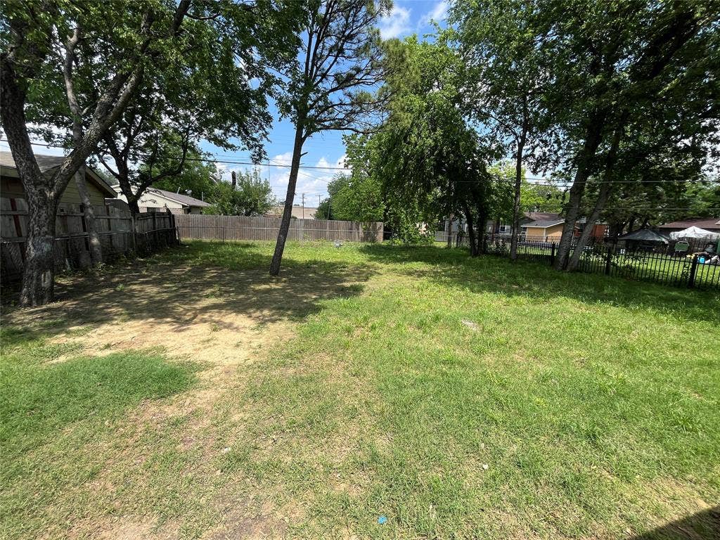 6415 Godfrey Avenue, Dallas, TX 75217 Expansive backyard featuring mature trees and perimeter wood and metal fencing