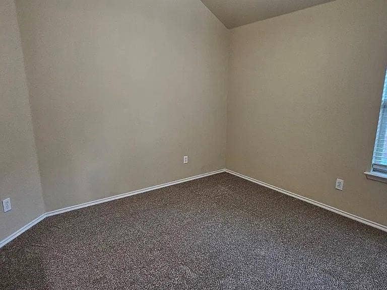 1000 Buffalo Creek Drive, McKinney, TX 75072 Neutral-toned interior space featuring vaulted ceilings, wall-to-wall carpeting, and a single window with blinds
