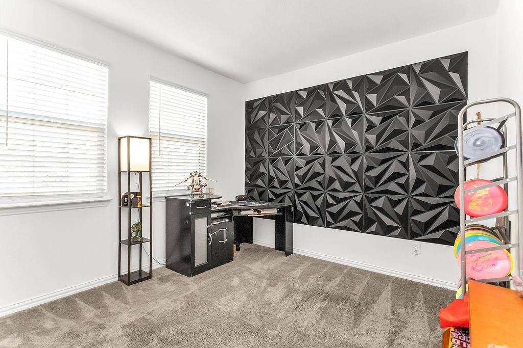 A bedroom that can be used as an office. Geometric black accent wall, wall-to-wall carpeting, and dual windows with horizontal blinds