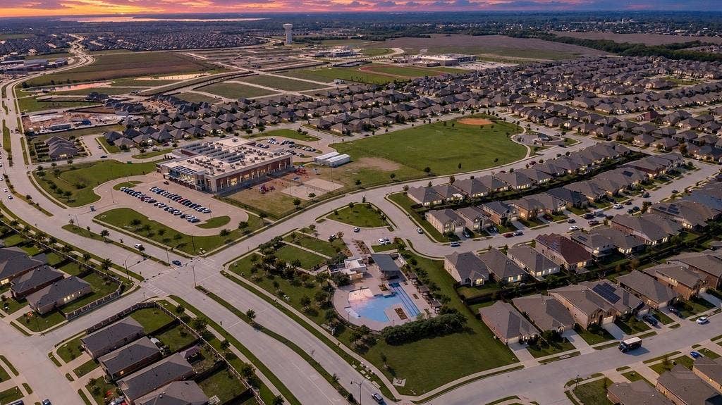 Aerial perspective of the community, highlighting a central recreational facility, swimming pool, expansive green space, and paved road infrastructure