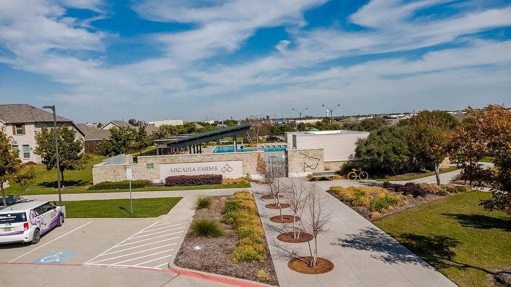 Community recreation area featuring a swimming pool, shaded pergola, paved walkways, and professional landscaping