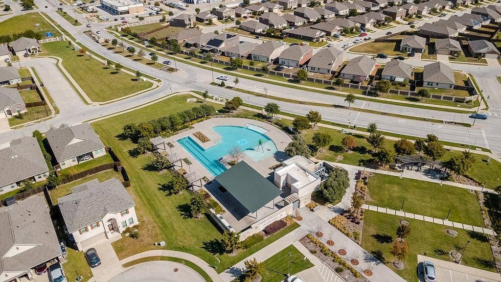 Community recreational area featuring an expansive swimming pool, covered pavilion, paved pathways, and manicured green space