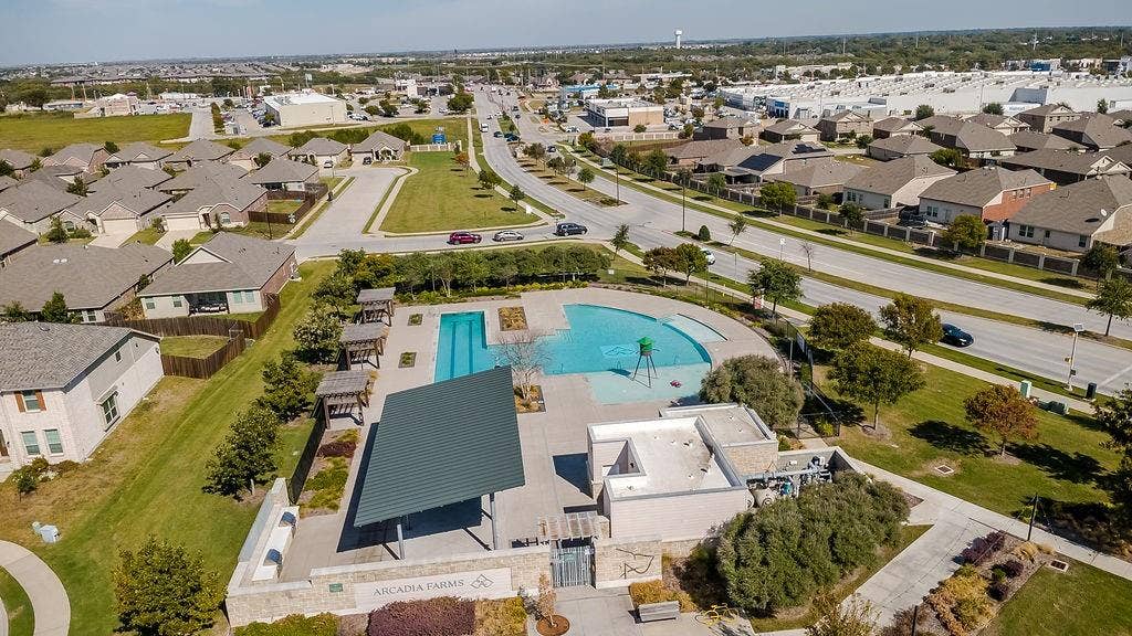 Community amenity center featuring a swimming pool, multiple pergolas, a covered pavilion, and stone-facade structures