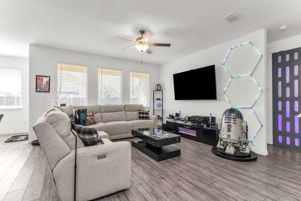 Living area featuring vinyl flooring, a ceiling fan, and multiple windows