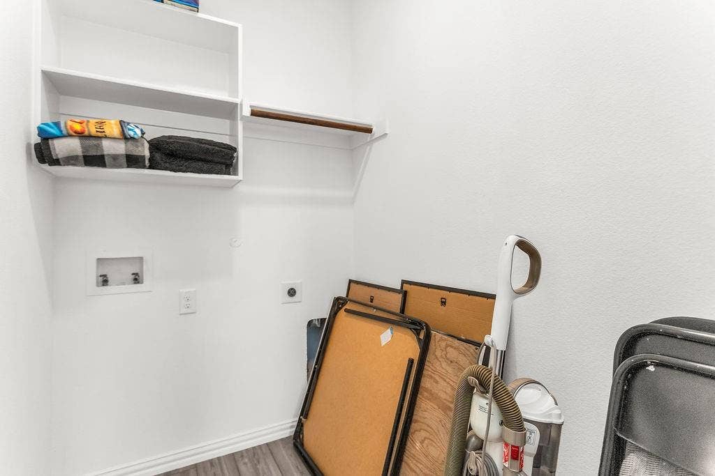 Utility area featuring wood-finish flooring, built-in white shelving, and an integrated hanging rod