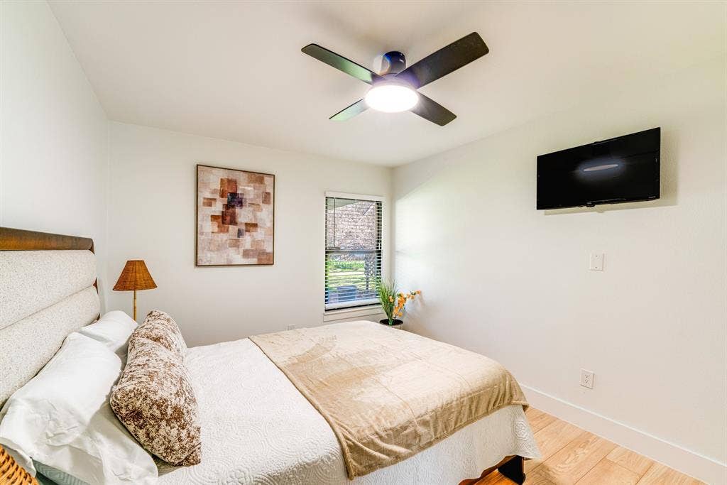 Neutral-toned interior featuring wood-finish flooring, a contemporary ceiling fan with integrated lighting, and a single-pane window with blinds