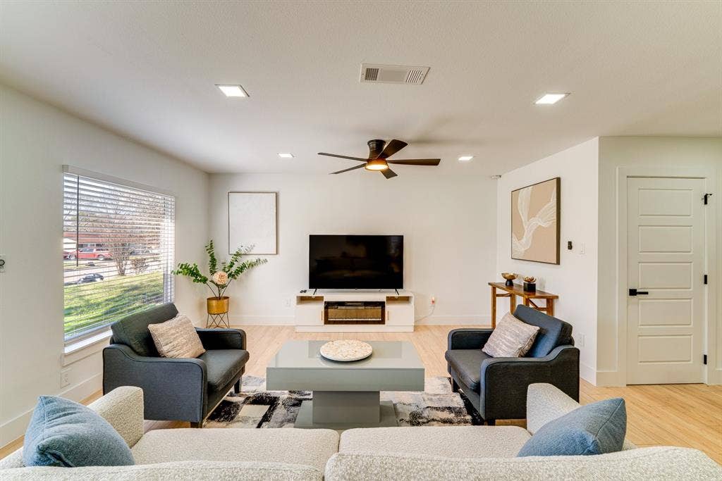 Living area featuring light-toned wood-finish flooring, recessed lighting, a ceiling fan, and a multi-panel door with matte black hardware
