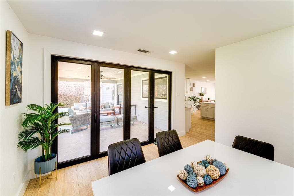 Black-framed glass folding doors, wood-finish flooring, and recessed ceiling lighting