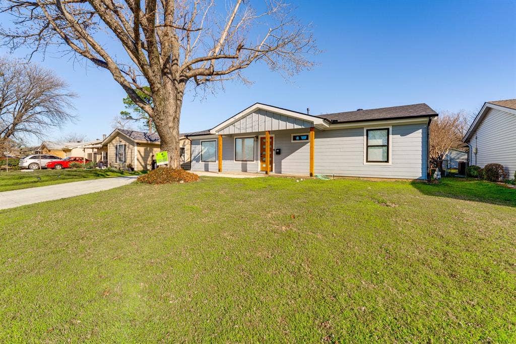 Single-story residence featuring horizontal lap siding, vertical board-and-batten gable accents, wooden porch support posts, and a concrete driveway