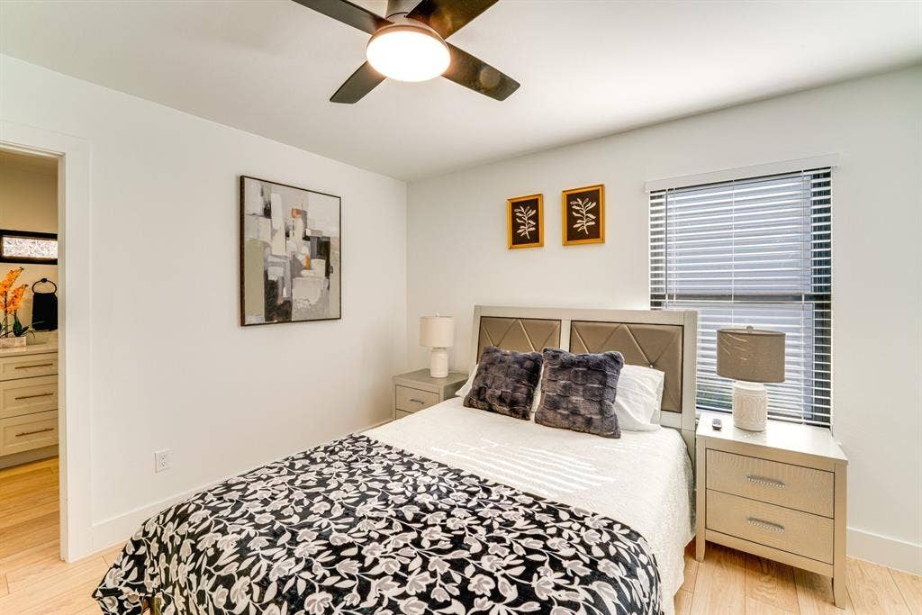 Room featuring light-toned wood-finish flooring, a ceiling fan with integrated lighting, and a window with horizontal blinds