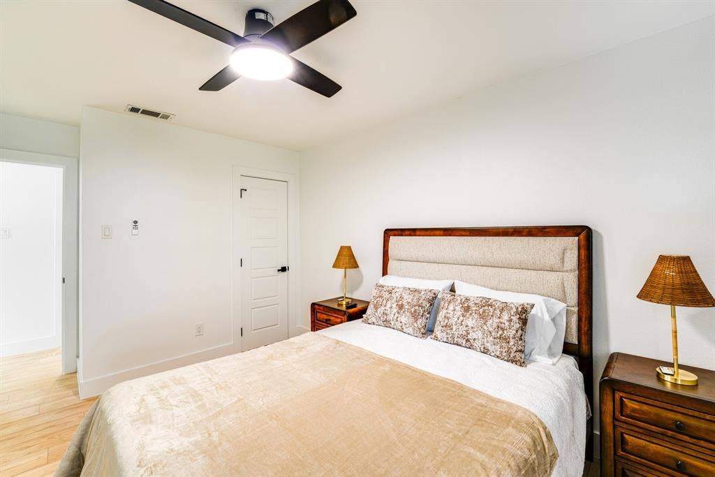 Wood-finish flooring, matte black ceiling fan with integrated lighting, and multi-panel interior door