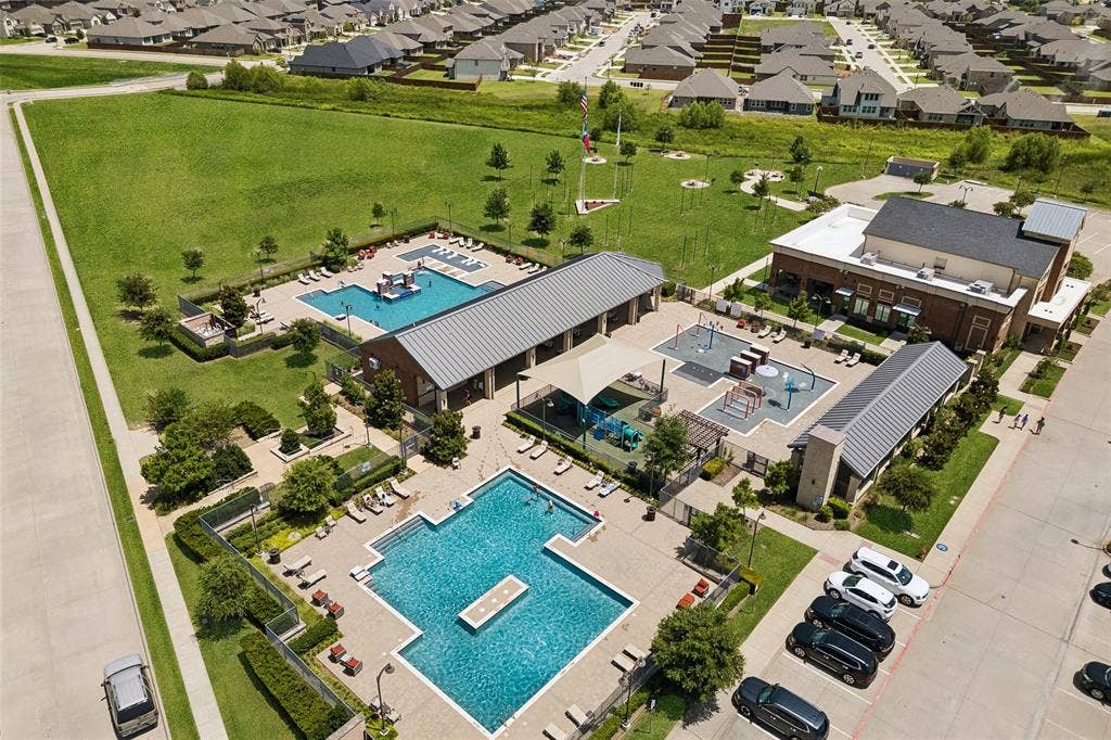 1321 Meridian Drive, Forney, TX 75126 Community amenities featuring two swimming pools, two separate children's play areas, a large open green space, and a clubhouse building with a brick exterior