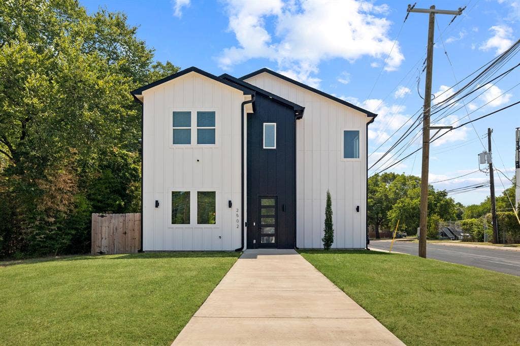 2502 Elsie Faye Heggins Street, Dallas, TX 75215 Two-story exterior featuring vertical white panel siding with black accent trim, a central entryway with a glass-paneled door, and a concrete walkway