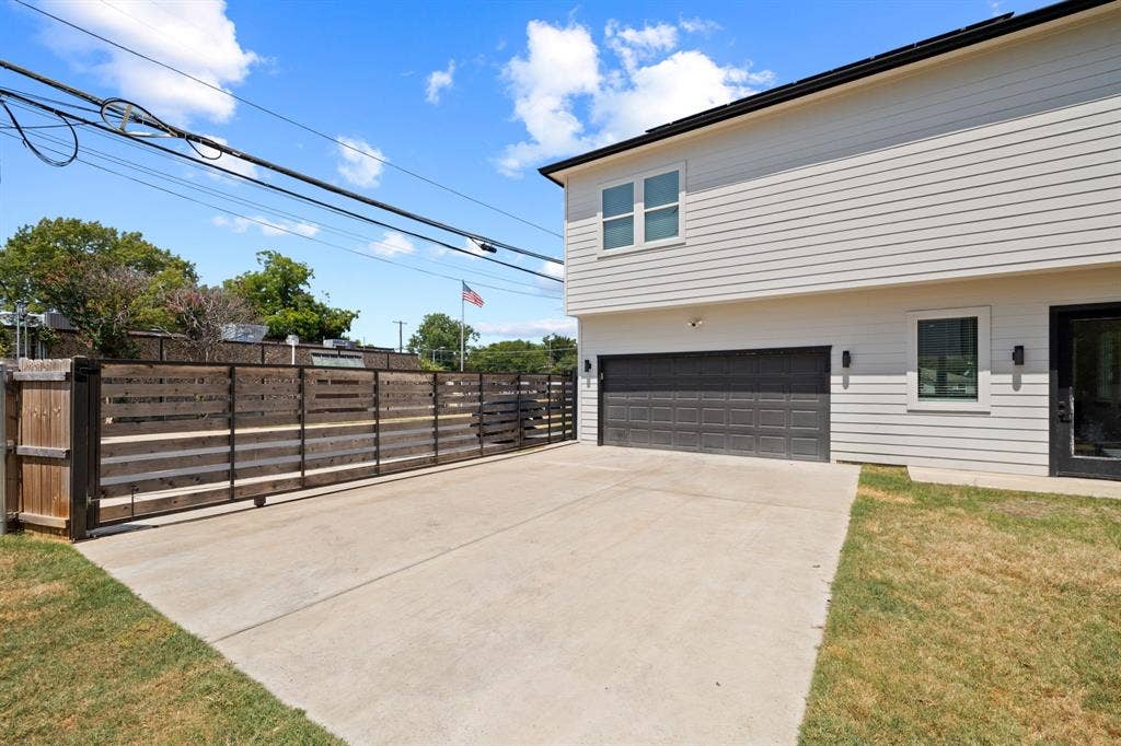 2502 Elsie Faye Heggins Street, Dallas, TX 75215 Exterior featuring horizontal siding, a multi-car garage with a paneled door, horizontal wood-slat privacy fencing, and a concrete driveway
