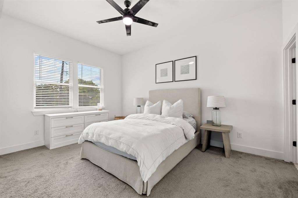 2502 Elsie Faye Heggins Street, Dallas, TX 75215 Neutral interior featuring plush wall-to-wall carpeting, high ceilings, large dual-pane windows with horizontal blinds, and a modern matte black ceiling fan with integrated lighting