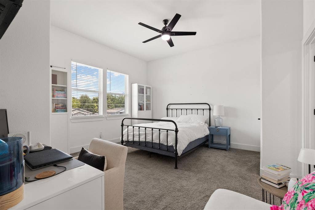 2502 Elsie Faye Heggins Street, Dallas, TX 75215 High-ceiling room featuring neutral carpeting, a ceiling fan with integrated lighting, dual windows, and built-in shelving