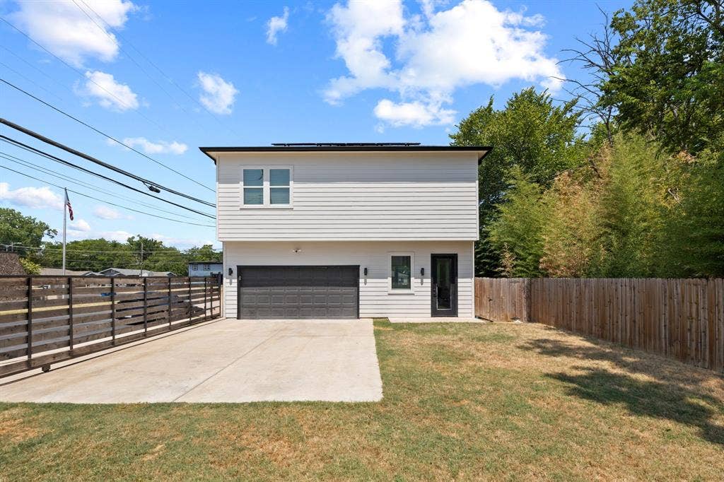 2502 Elsie Faye Heggins Street, Dallas, TX 75215 Two-story exterior featuring horizontal siding, a private concrete parking pad, a two-car garage with a paneled door, and wood-style fencing