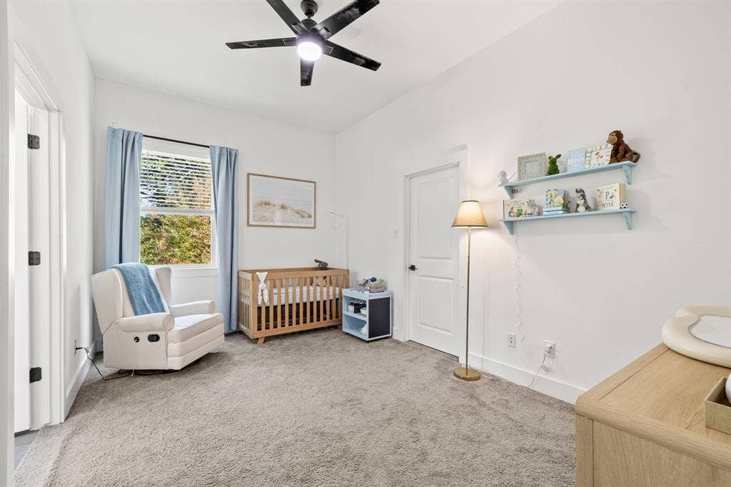 2502 Elsie Faye Heggins Street, Dallas, TX 75215 Neutral-toned carpeting, matte black ceiling fan, single-hung window with exterior view, and solid core interior door with matte black hardware