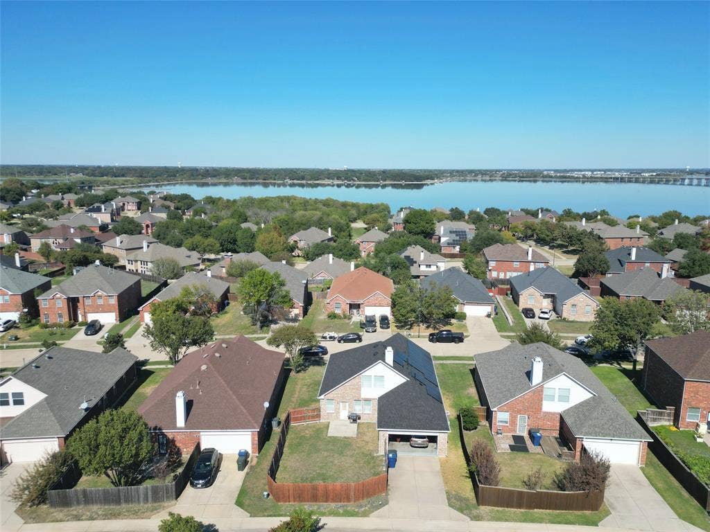 4102 Maidstone Drive, Garland, TX 75043 Wide aerial view showing the home within the surrounding neighborhood, including nearby streets, rooftops, and water visible in the distance.