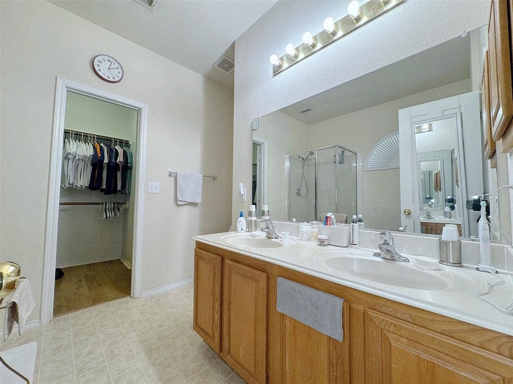 4102 Maidstone Drive, Garland, TX 75043 Alternate bathroom view highlighting the long wood vanity, mirror, overhead lighting, and countertop with sinks.