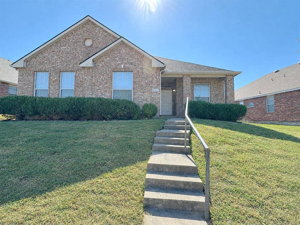 4102 Maidstone Drive, Garland, TX 75043 Front exterior of 4102 Maidstone Drive, featuring a brick facade, gabled roofline, lawn, and stepped walkway leading to the covered entry.