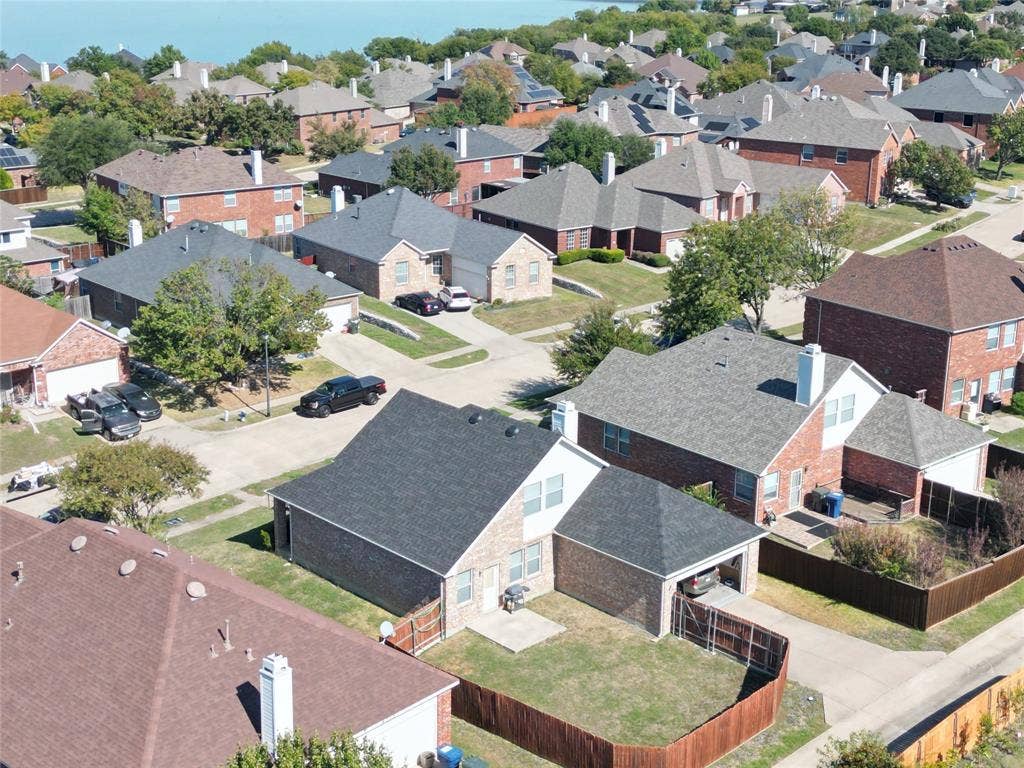 4102 Maidstone Drive, Garland, TX 75043 Oblique aerial view showing the rear of the home, roofline, fenced yard, driveway, and surrounding residential lots.