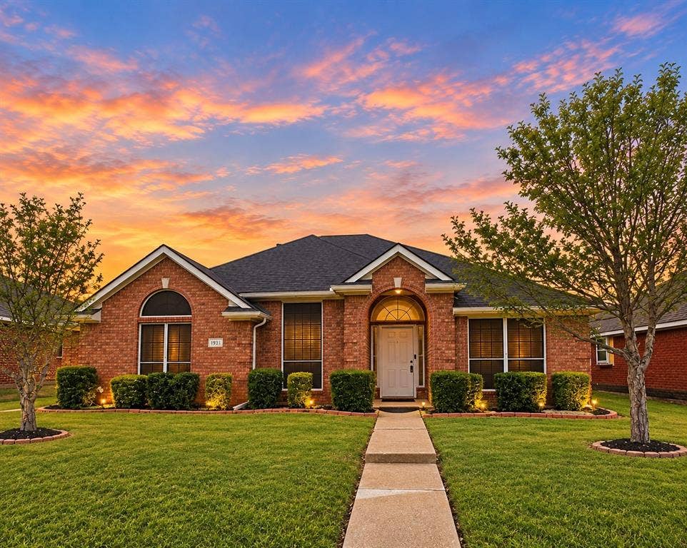 1931 Cutler Drive, Mesquite, TX 75149 Brick exterior featuring an arched entryway, arched window accents, dark shingle roof, and a concrete walkway
