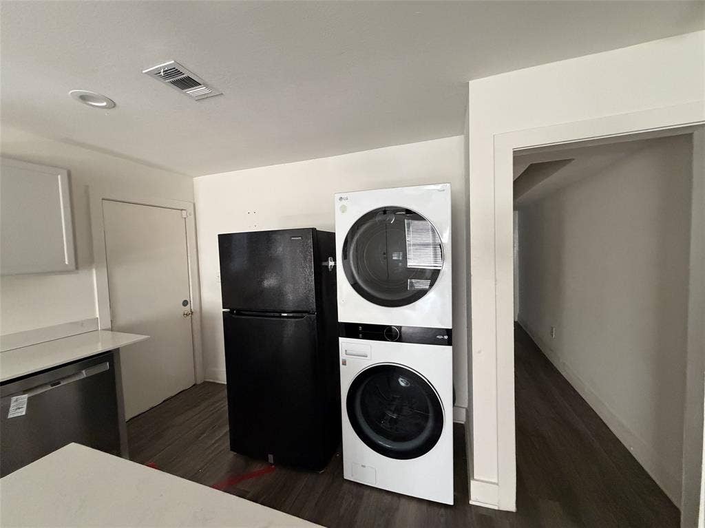 Utility in kitchen with stackable and fridge.