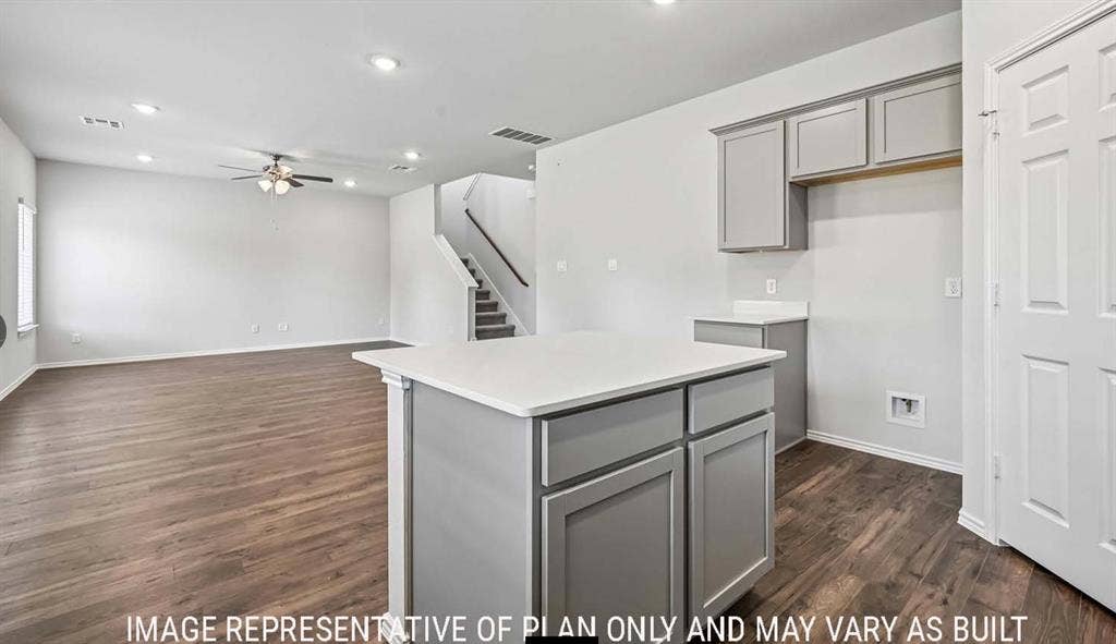11709 Ceres Street, Lorena, TX 76655 Kitchen island with white countertop and grey cabinetry, wood-finish flooring, recessed lighting, and a staircase featuring a wooden handrail