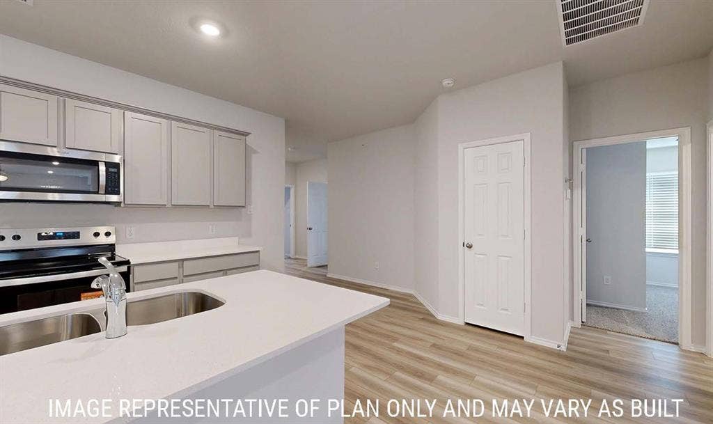 3213 Cyprian Road, Lorena, TX 76655 Kitchen featuring light-toned cabinetry, solid-surface countertops, an integrated double-basin stainless steel sink with a high-arch faucet, stainless steel appliances, and wood-finish flooring