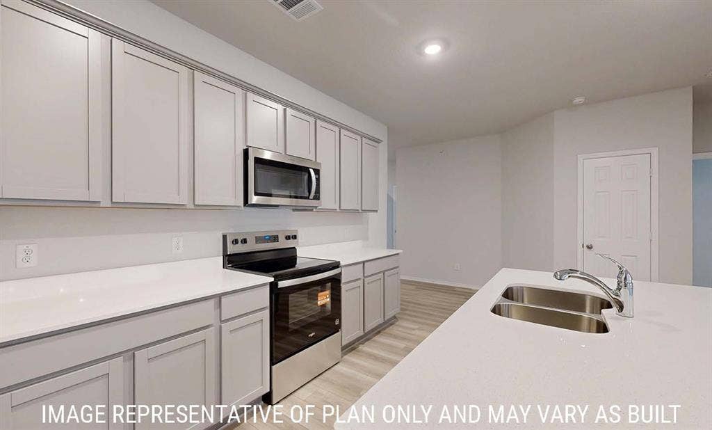 3213 Cyprian Road, Lorena, TX 76655 Kitchen featuring shaker-style cabinetry, solid-surface countertops, stainless steel appliances, a central island with an integrated dual-basin sink, and wood-finish flooring